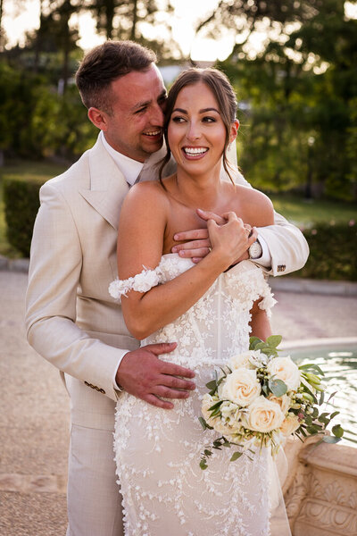 Bride and groom embracing during sunset by a fountain at their wedding venue