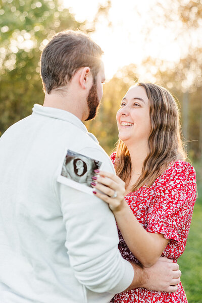 Couple smiling outdoors holding sonogram image