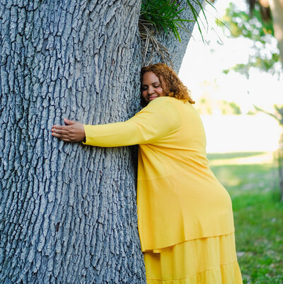 Certified life coach Claudine Martinell embracing the tree, showing warmth of connection and intimacy.