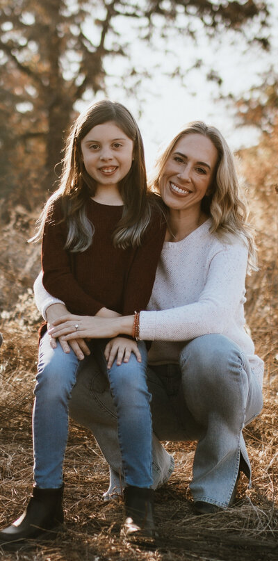 Mom and daughter sitting together in a sunlit field during golden hour – reflecting on raising third culture kids on the Leaving Main Street parenting abroad blog