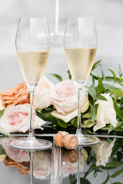 filled champagne flutes on the hood of vintage car with flowers in the background