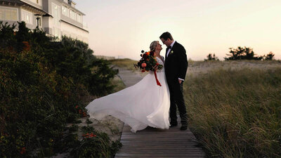 Couple standing on the boardwalk next to Dune with dress waving in the wind