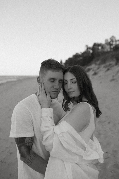 Engaged couple hugging each other on the beach