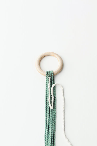 gathering knot white and green string on a wooden hoop