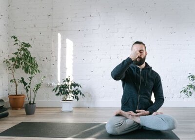 A man places his hand on his forehead, assuming a meditative posture