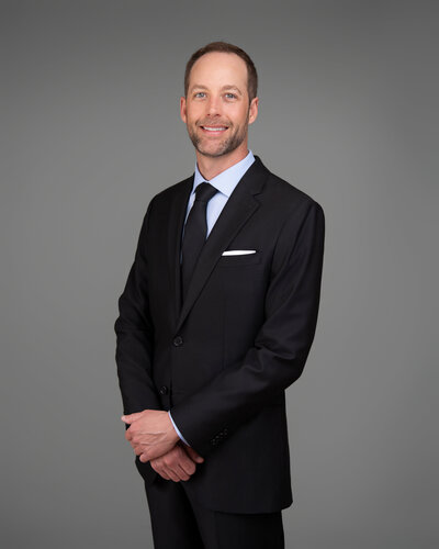 Professional Attire Headshot Man wearing suit and tie poses in front of clean background