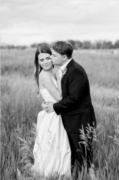 Bride and groom embrace in a grassy field