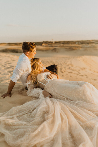 bride and groom laying down on beach