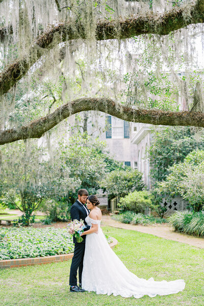 Bride and groom posing underneath the oaks trees at Pebble Hill Plantation on their wedding day