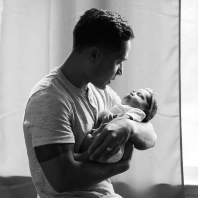 Father holds newborn daughter in military housing