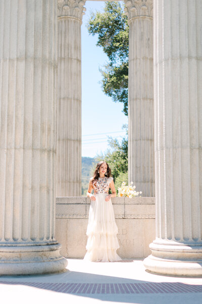 Bride in floor length cream embroidered Mac Duggal gown leaning against column of Pulgas Water Temple portraits, photo by Anastasiya Photography - San Francisco Photographer