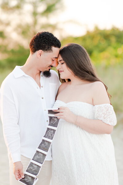 mom and dad with ultrasound on the beach in florida by miami maternity photographer msp photography David and Meivys Suarez