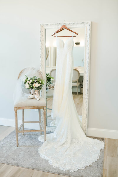 wedding dress hanging in front of a mirror