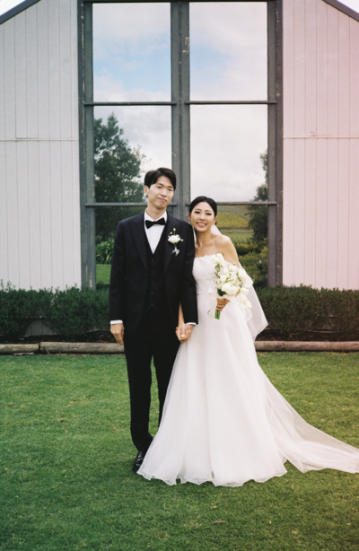 Couple holding hands in front of chapel, after their wedding ceremony shot on 35mm film