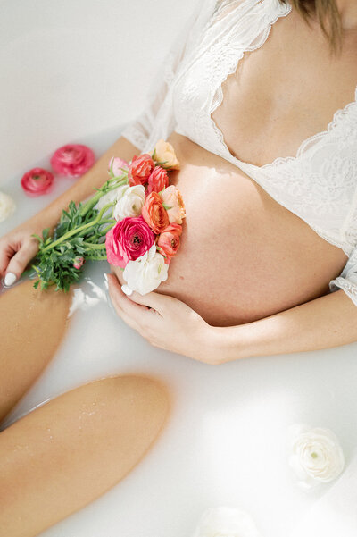 an intimate maternity session with a mother in a milk bath with an exposed belly