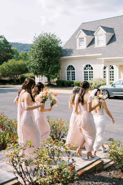 Bride and bridesmaids in pink dresses holding bouquets and walking outside