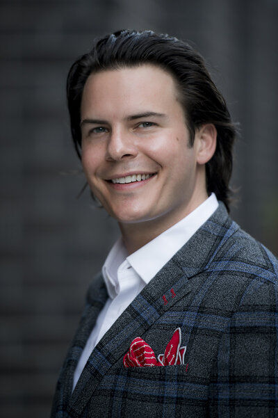 A person in a suit looking to the side and smiling 