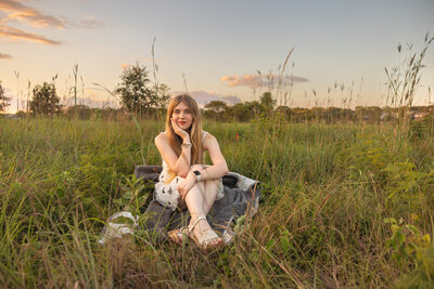 Senior photo session of Lily sitting on a blanket in a field at the Arboretum in Lawrence, KS | Senior Photographer in Lawrence, KS