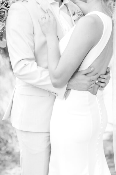 Groom pulling in his bride for an intimate hug while holding both of his hands on her back