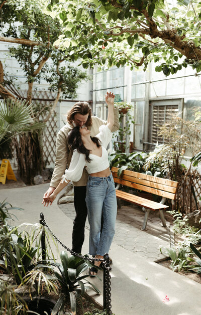 couple standing snuggled up inside a greenhouse