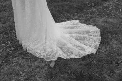 A black and white photo of a brides lace wedding dress. 