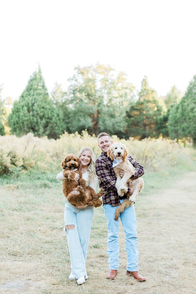 a couple holding their dogs in the woods