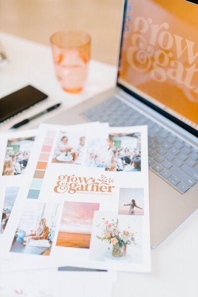 Laptop open on white desk with brand elements and pink cup