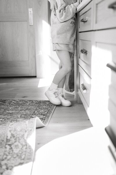 Child in their Nashville home standing at the kitchen counter in black and white 