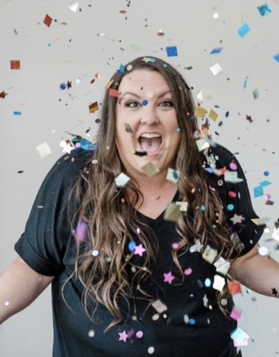 Client review for search engine advertising, featuring color confetti and the reviewer dressed in a dark blue blouse, highlighting positive feedback and celebration of successful advertising results.