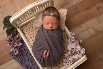 Baby girl wrapped in purple on white bed