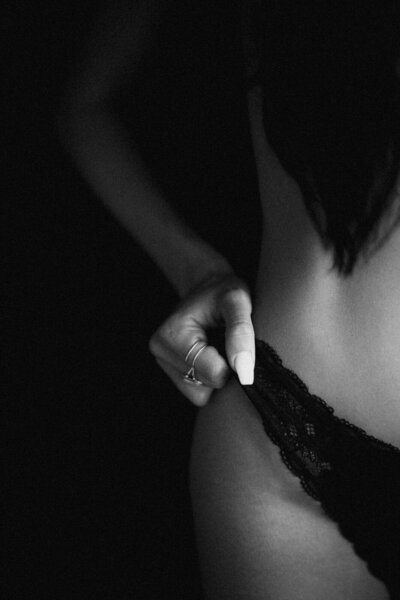 A close-up of a woman adjusting her black lace lingerie during a Boudoir Phoenix photoshoot, highlighting elegance and intimate detail.