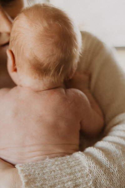 Mother cradles her naked newborn baby