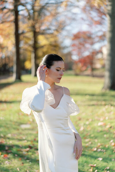 Elegant bride in modern gown posing outdoors with autumn foliage