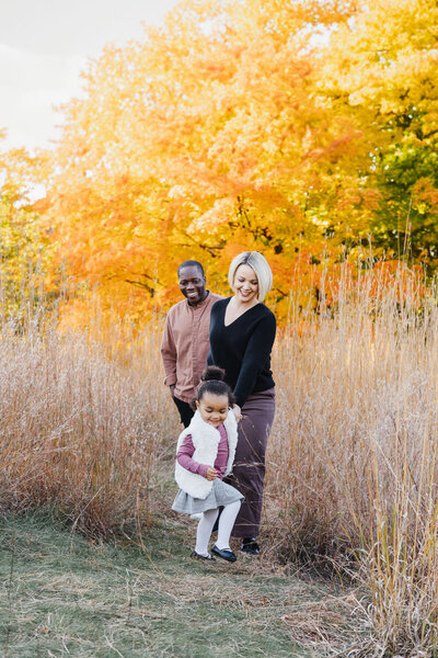 Little girl running in front of parents in High Park