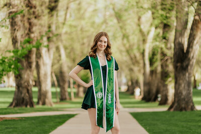 A proud Colorado State University graduate poses for a photo during her grad photo session in Fort Collins, Colorado.