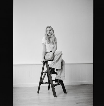 Black and white photo of Fallon Stovall standing on the street in a trenchcoat