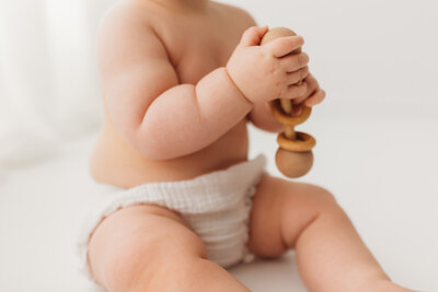 Maternity session of baby holding rattle in studio
