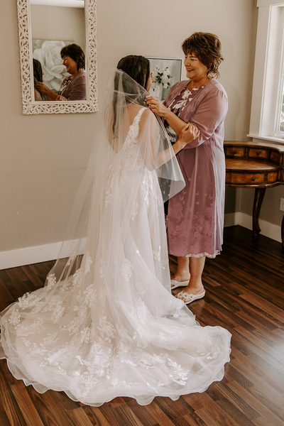 Trisha and her mom sharing a moment fixing her veil with heirloom lace.