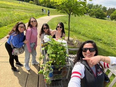 DC Stationery Designer & Calligrapher promoting sustainability and eco-friendly business, pushing a shopping cart full of plants