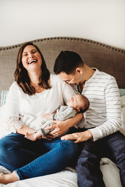 mom and dad laughing with newborn