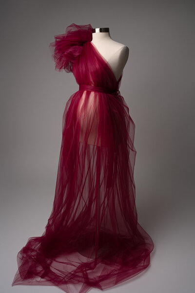 Deep merlot one-shoulder maternity tulle gown with large shoulder ruffle and sheer flowing skirt
Description: