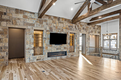 rustic living room with stone wall gas fireplace and wood beams