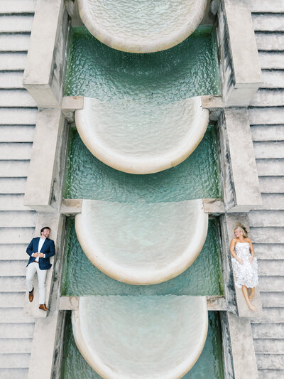 Bride and groom look at each other across the Swan house Fountain during engagement session in Atlanta Georgia
