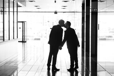 An Austin-based wedding photographer captures an intimate moment between two business men kissing in a hallway.