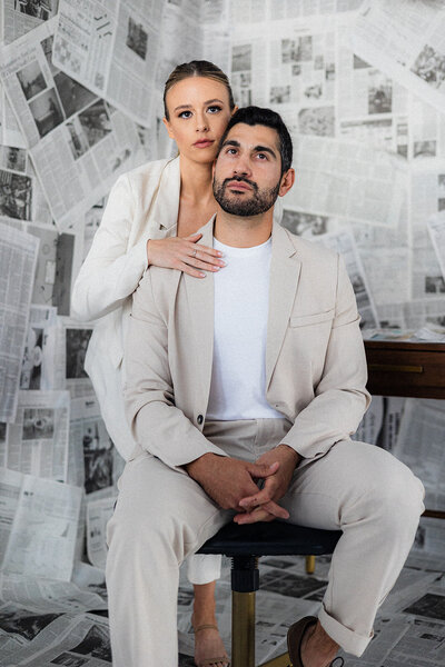 A couple stands in front of newspapers