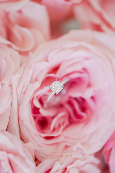 Pink peony holds a solitaire engagement ring