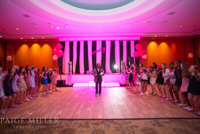 Teens and DJ dancing under pink lights