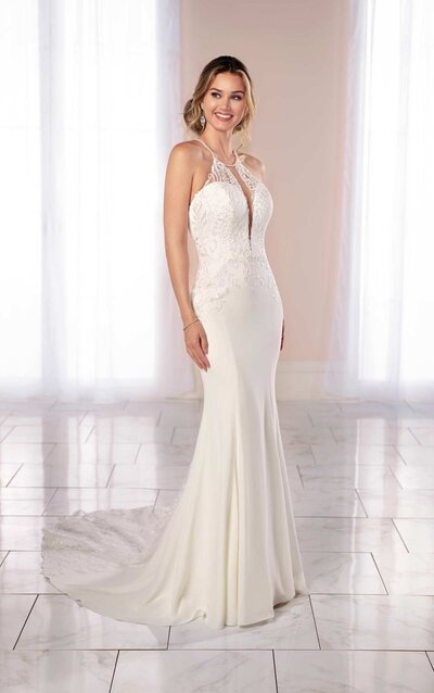 MODERN MIXED-FABRIC WEDDING GOWN WITH HIGH HALTER NECKLINE This sultry and stylish silhouette from Miss Stella York is perfect for an adventurous wedding day statement. Lace over crepe gives a softer, lighter feel that is both easy to wear and effortlessly sexy—making it the perfect accompaniment to a beach or garden wedding. A high neckline with skinny center plunge offers a hint of modern sexiness, while light beadwork offers the touch of decadence you crave. Curved seaming and graphic laces are thoughtfully placed along the figure to flatter the curves for a universally flattering silhouette, while a long lace inset feature in the middle of the train widens toward the hem for a stunning hourglass effect. Floating laces and an X-back feature top the look with simple yet stunning detail, keeping all eyes on you ask you walk toward wedded bliss.