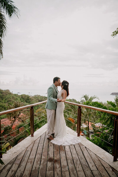 wedding couple standing on deck with ocean view