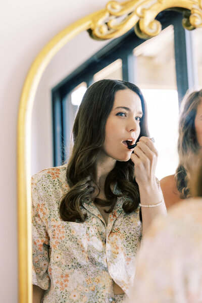 The bride applies makeup in the bright space next to a bridesmaid at Paint Rock Farm in North Carolina.